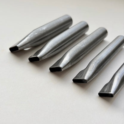 Six metallic oblong punches for leather on a white background