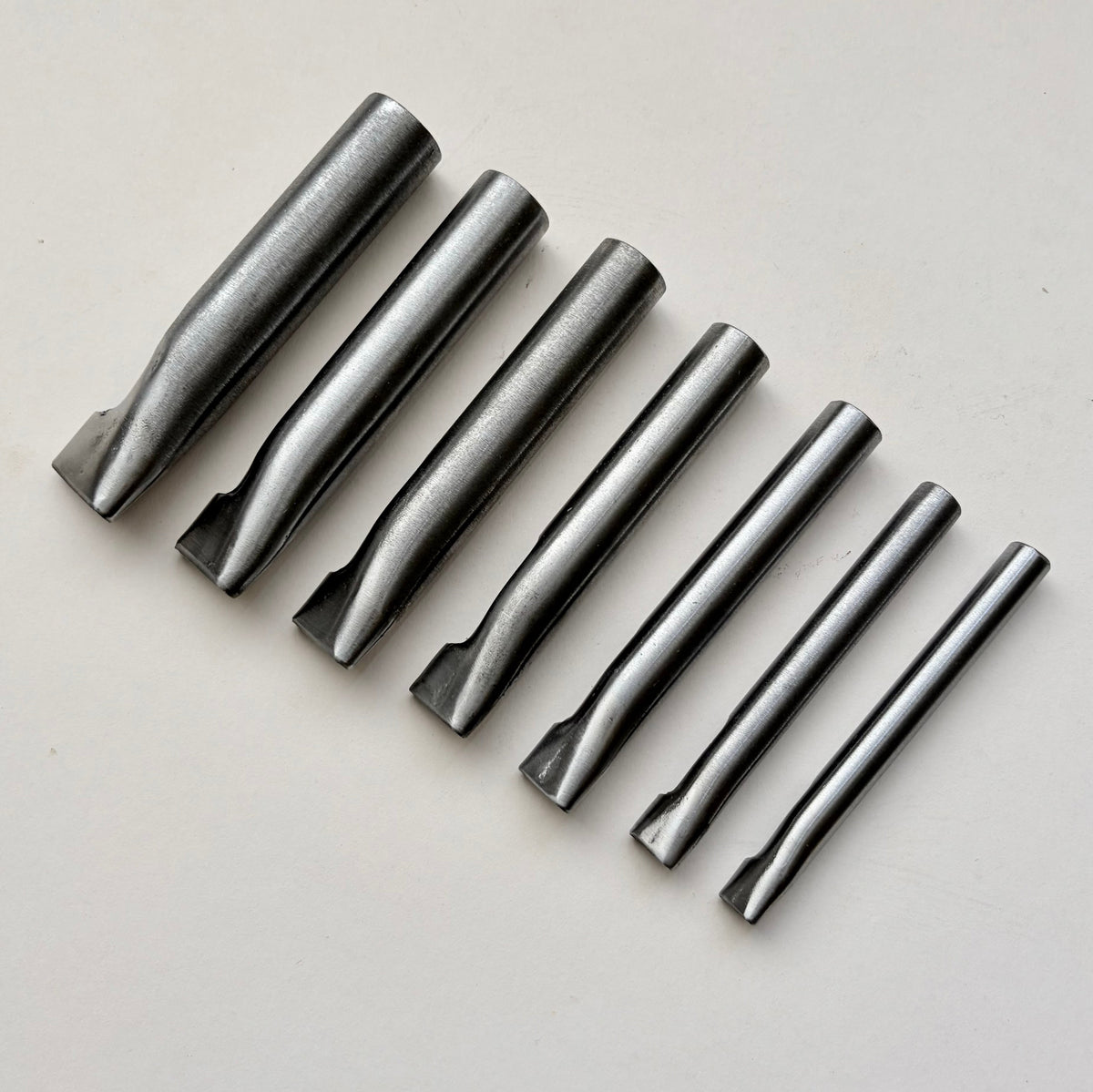 Six metallic oblong punches for leather on a white background