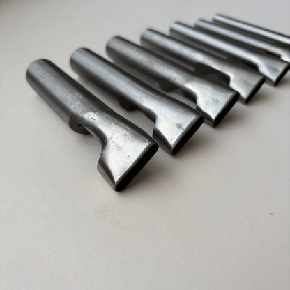 Six metallic oblong punches for leather on a white background