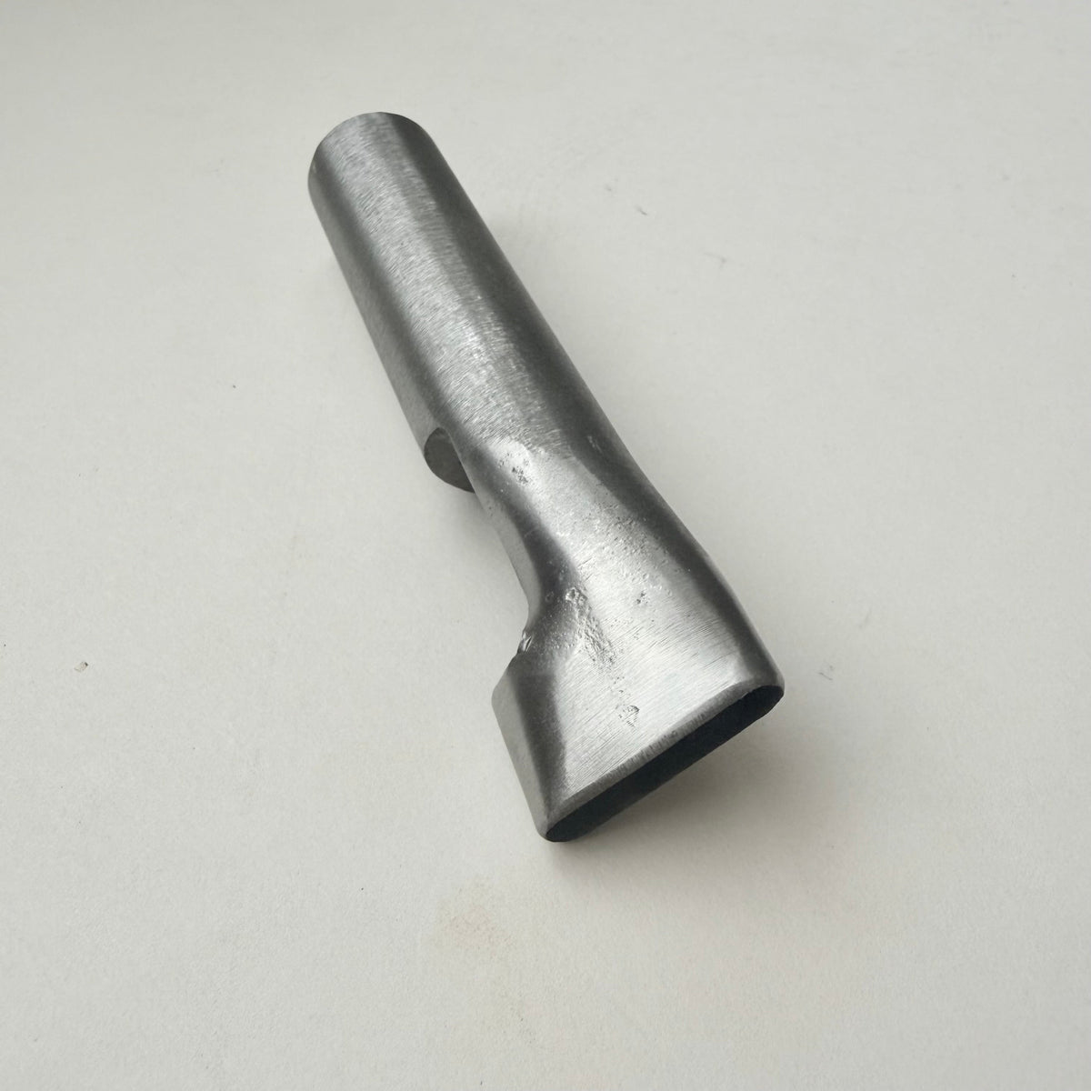 A metallic oblong punch for leather on a white background