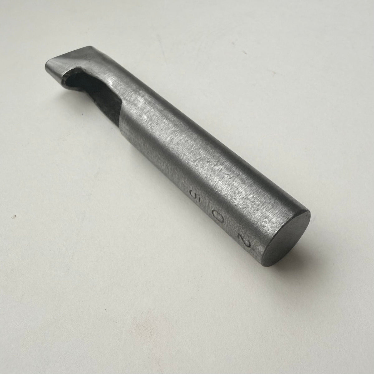 A metallic oblong punch for leather on a white background