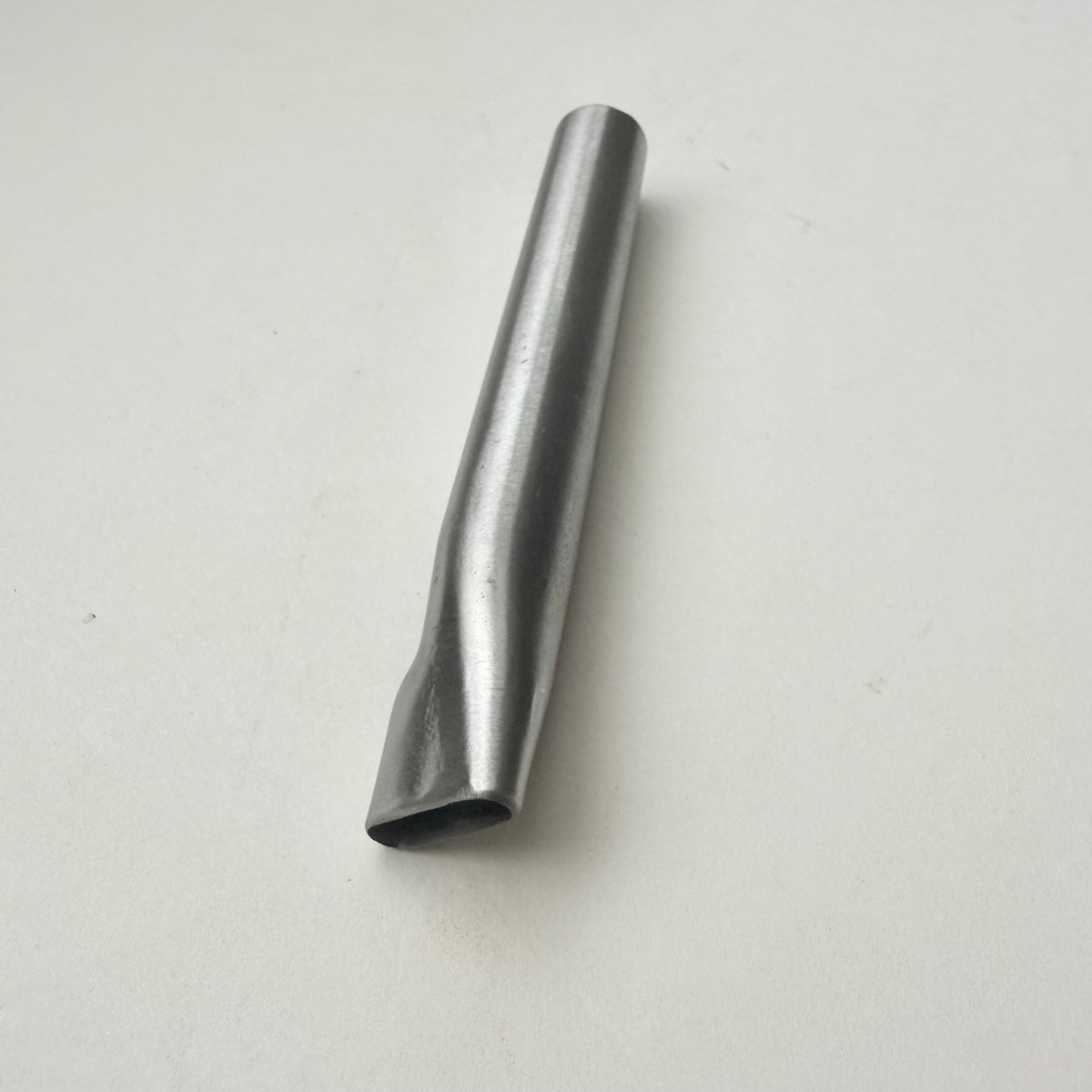A metallic oblong punch for leather on a white background