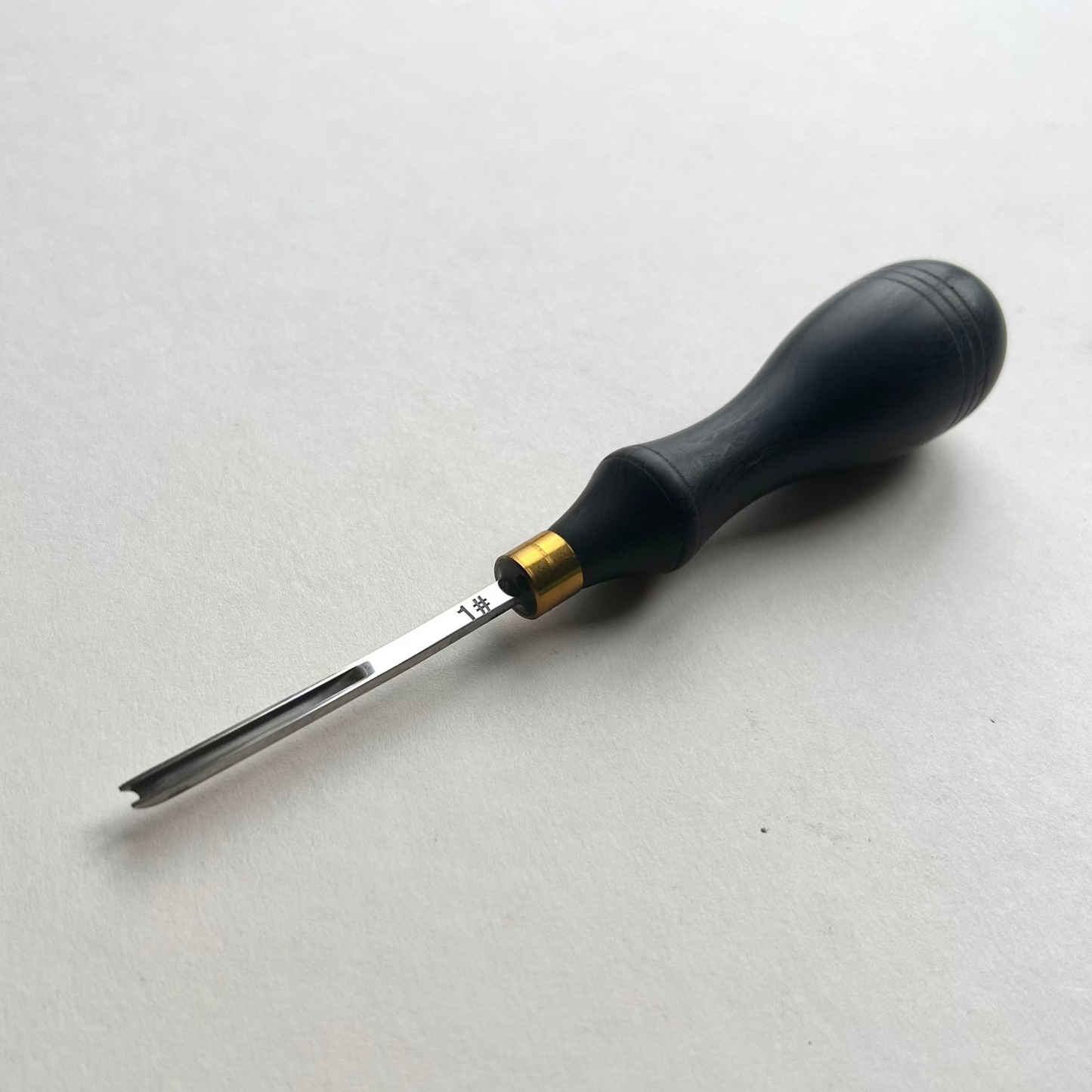Ebony-handled leather edge beveller on a white background