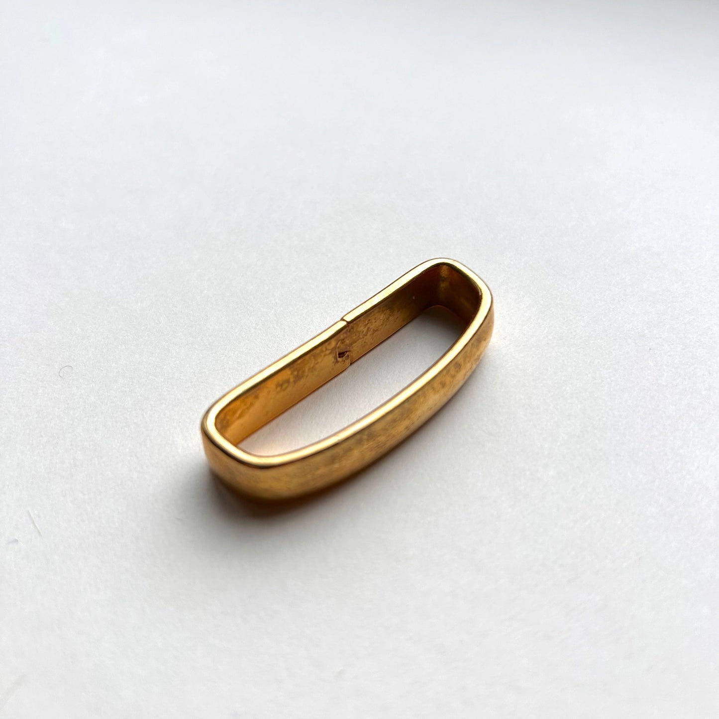 Solid brass gold belt loop keeper on white background