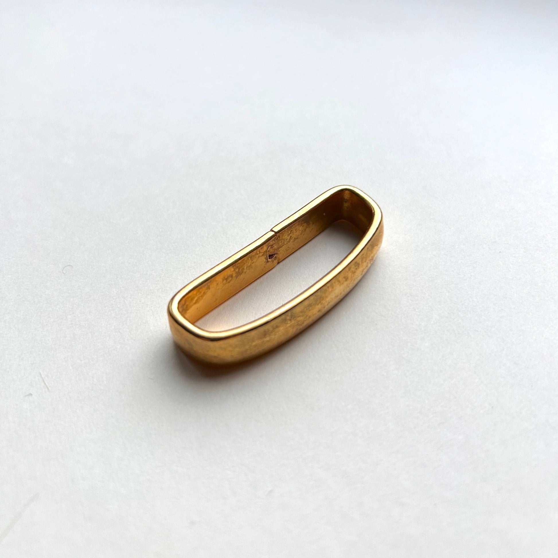 Solid brass gold belt loop keeper on white background
