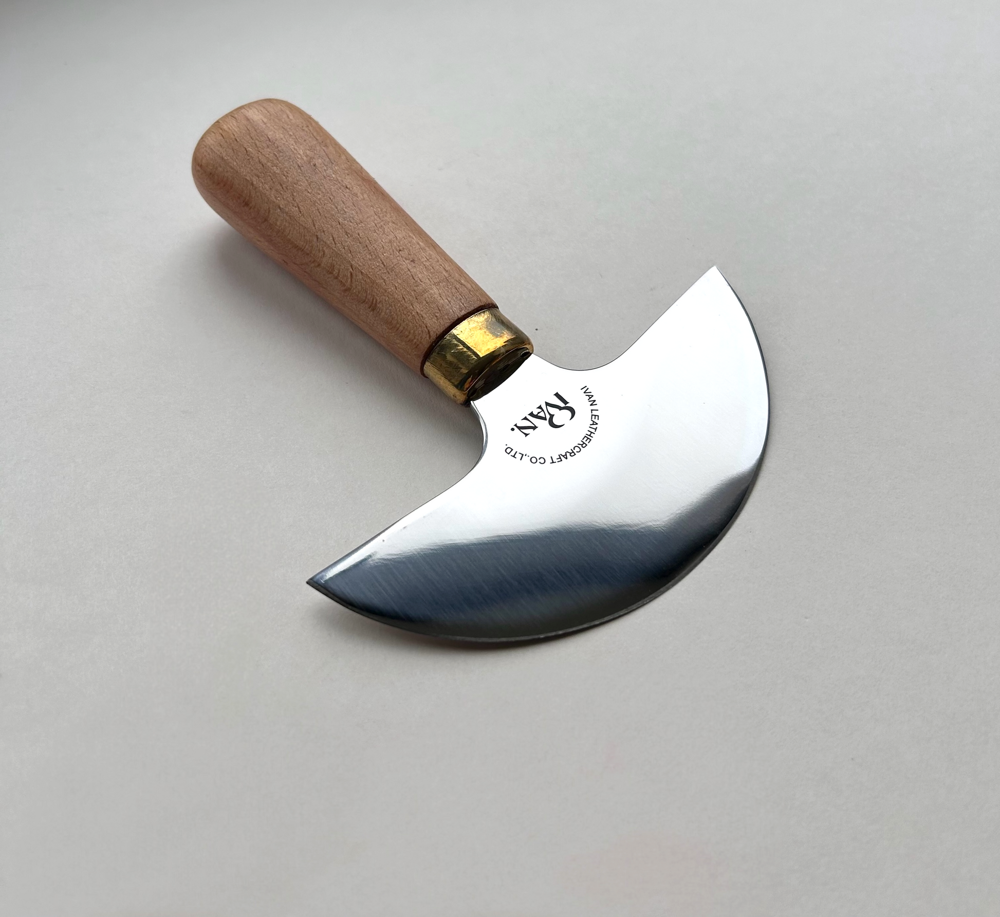 Round head leather knife with wooden handle on a grey background