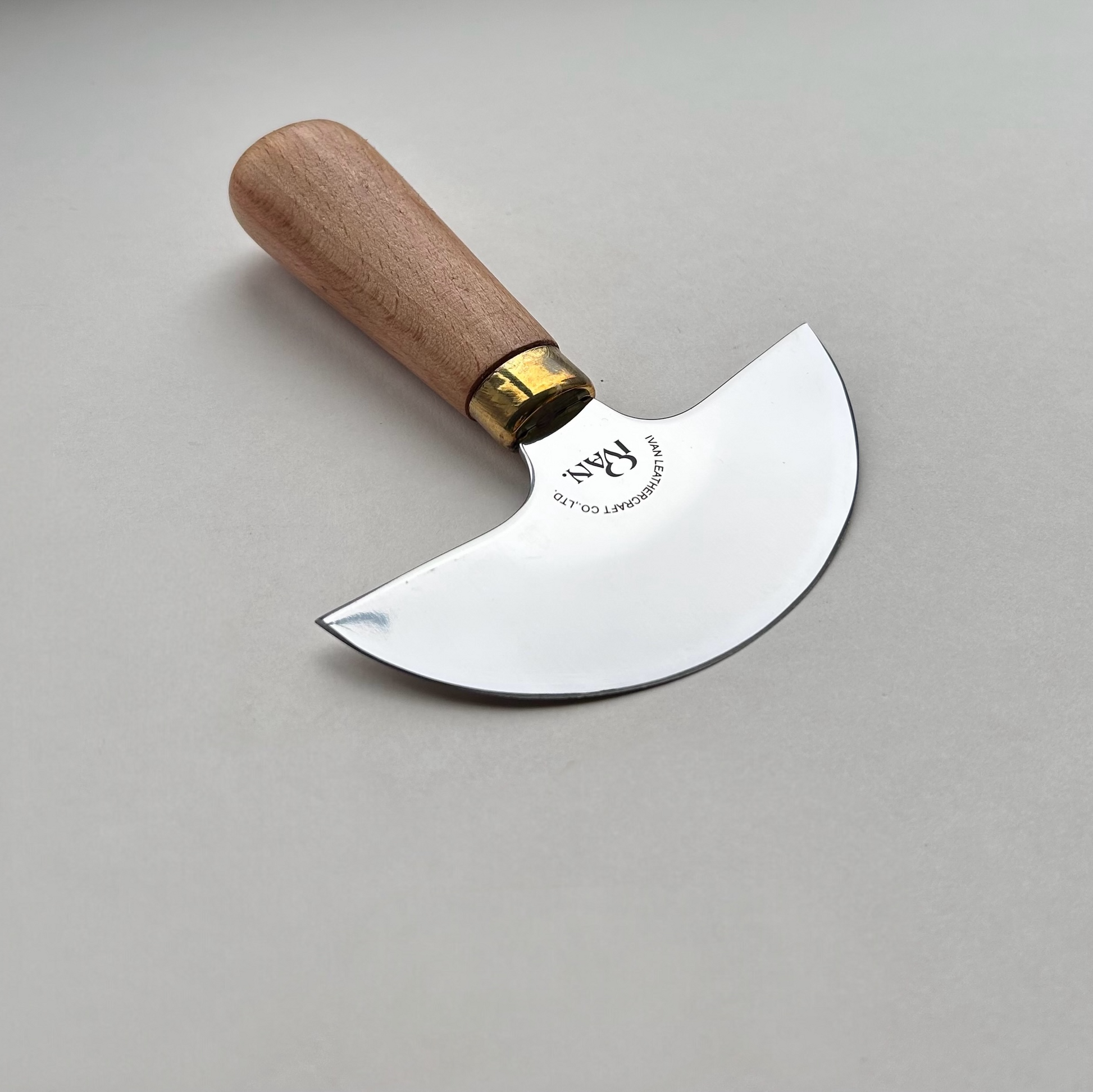 Round head leather knife with wooden handle on a grey background