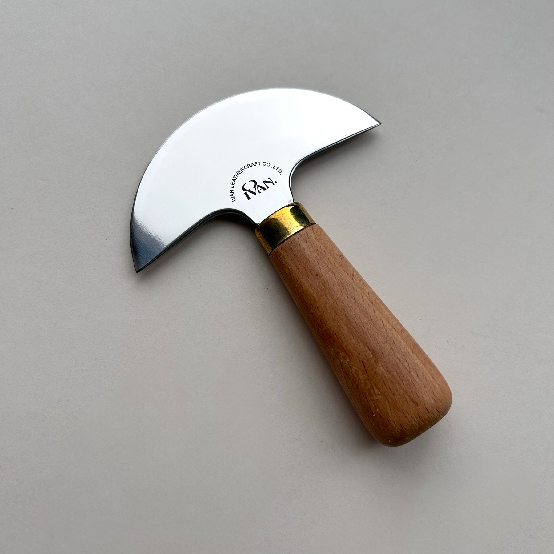 Curved leather knife with wooden handle and metal blade on a grey background