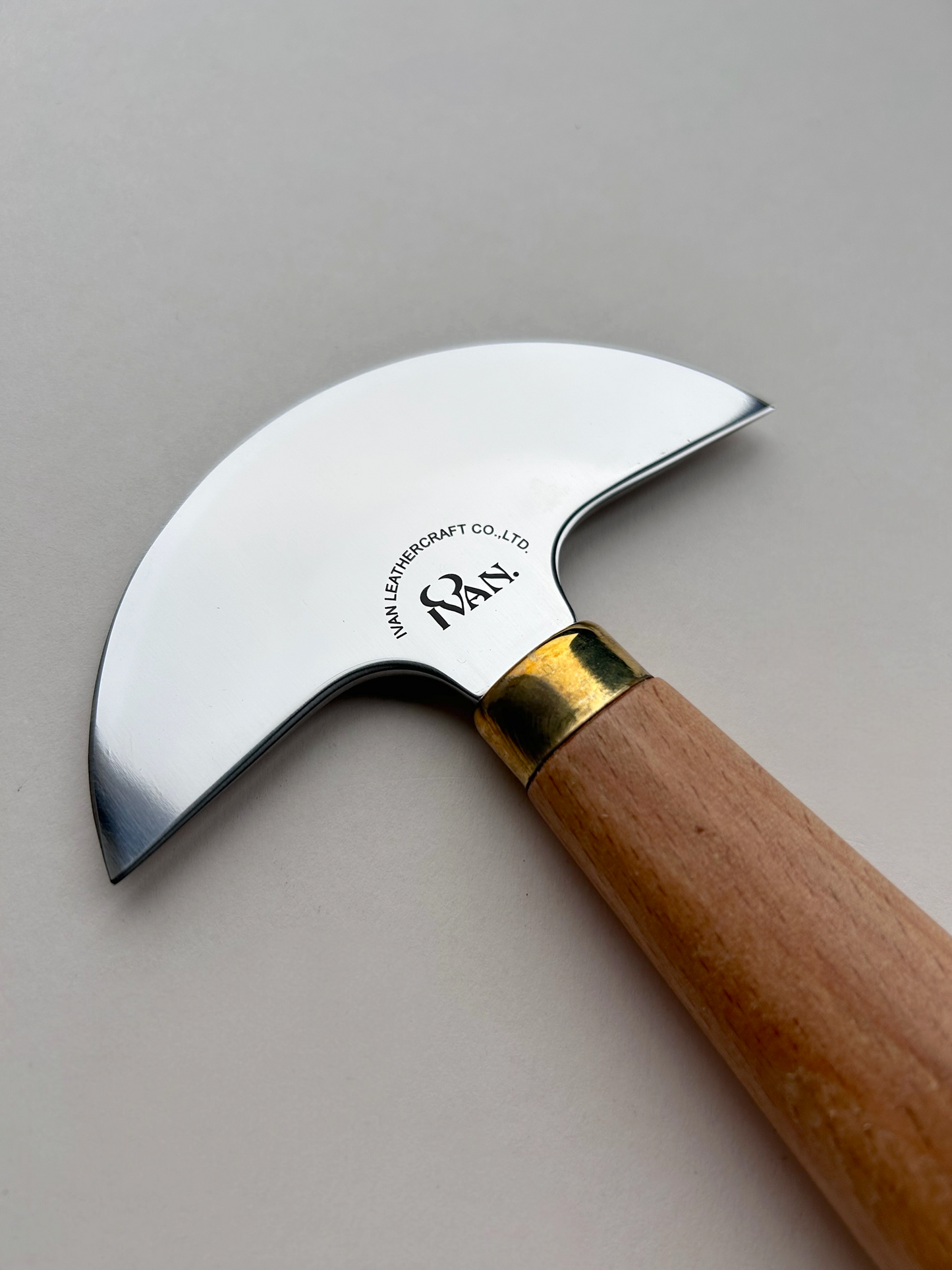 Round head leather knife with wooden handle on a grey background
