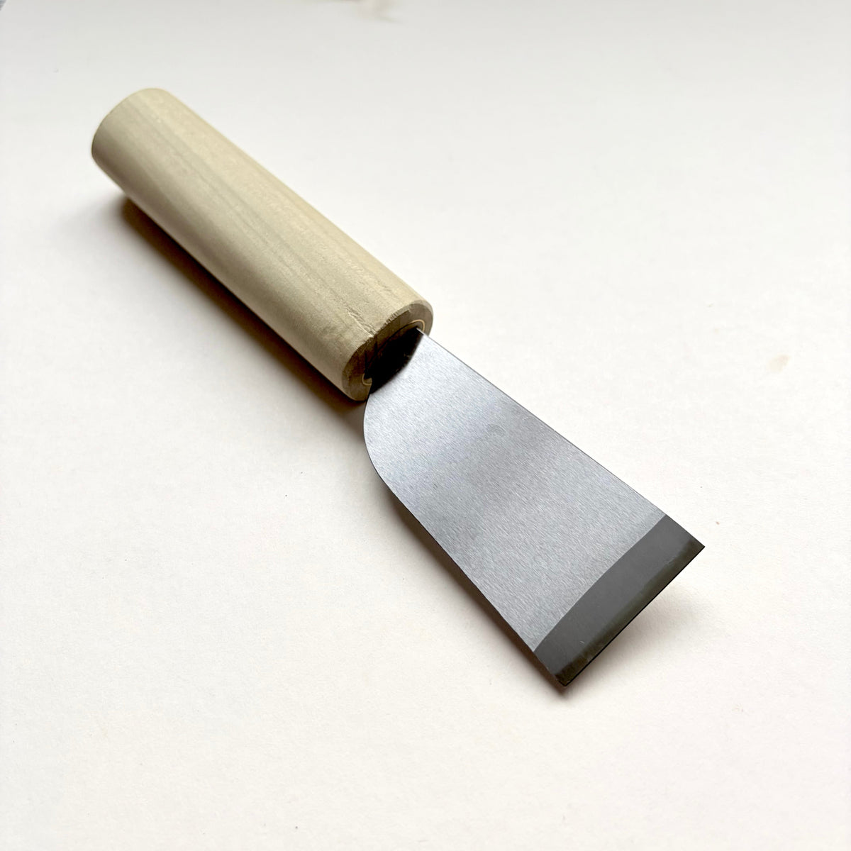 A Japanese-style wooden knife for leather with a light natural wood handle and a silver steel blade, photographed on a plain off-white background.