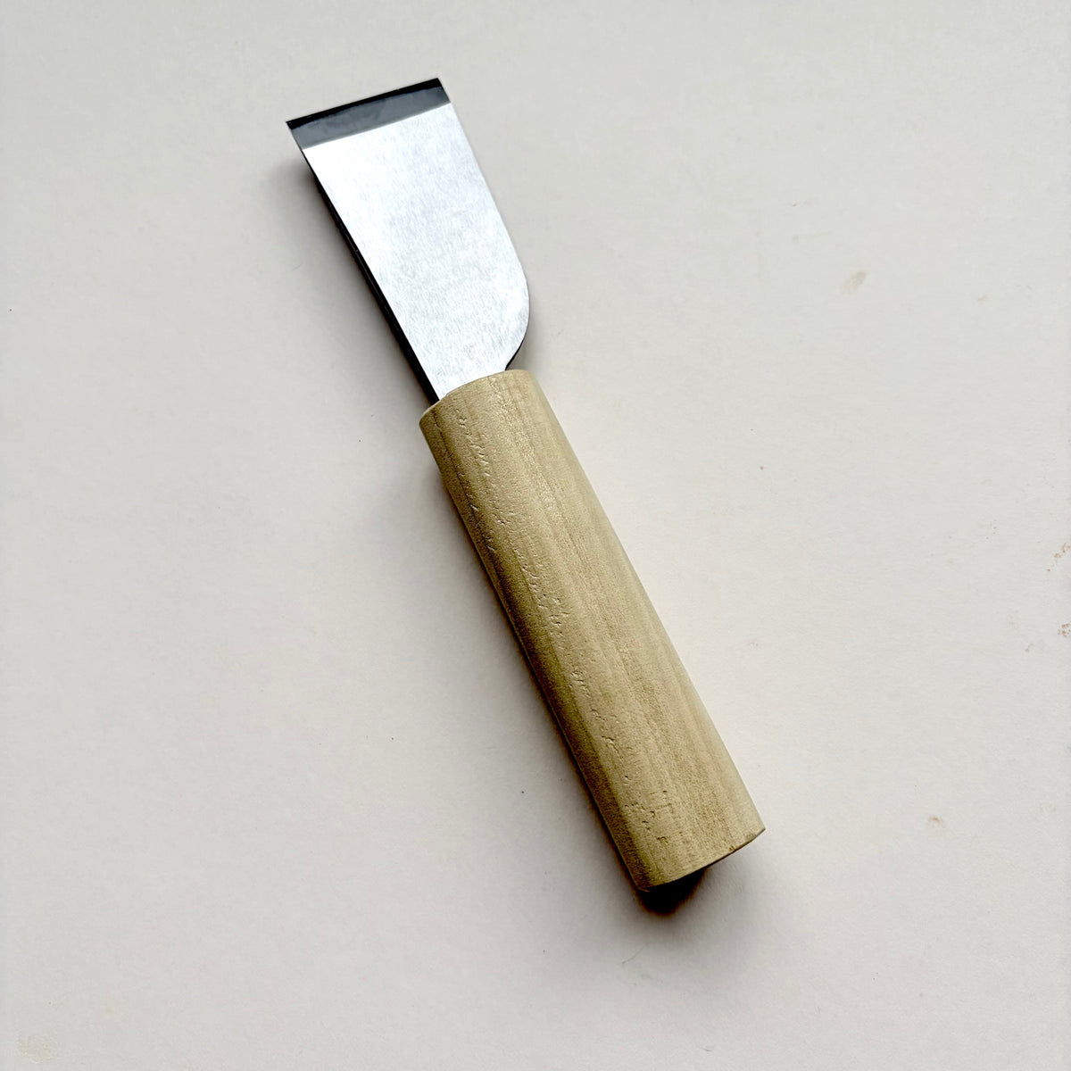 A Japanese-style wooden knife for leather with a light natural wood handle and a silver steel blade, photographed on a plain off-white background.
