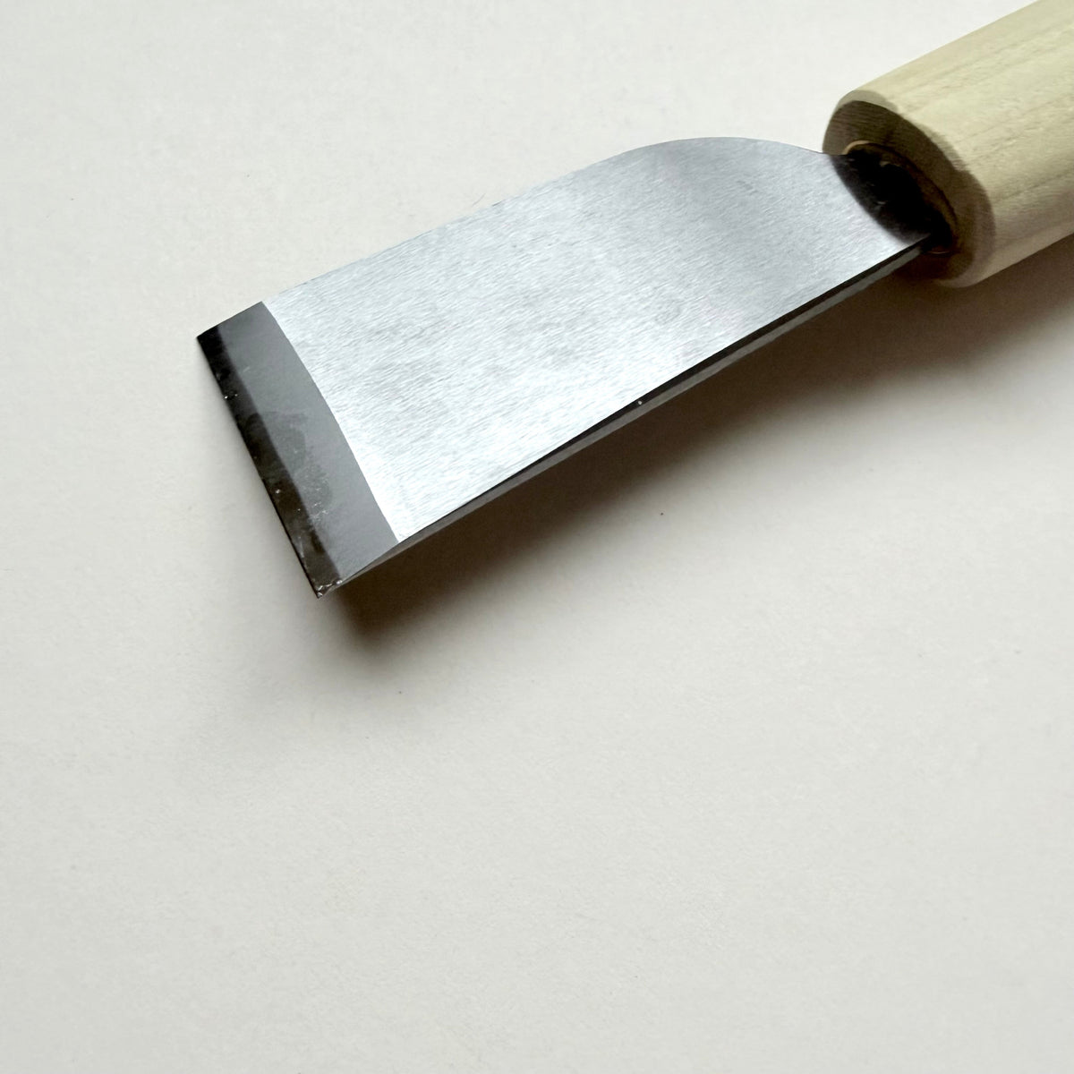 A Japanese-style wooden knife for leather with a light natural wood handle and a silver steel blade, photographed on a plain off-white background.