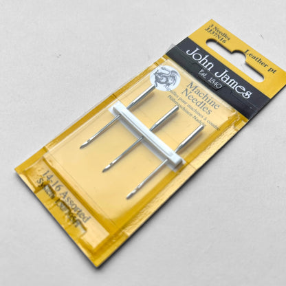 Packaged John James sewing machine needles on a grey background