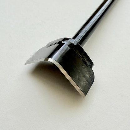 A black metal corner punch for leather with a long straight black handle, photographed on a plain light grey background.