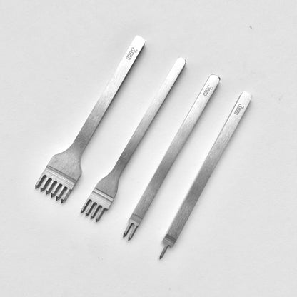 Set of four metal leather stitching punches on a light grey background