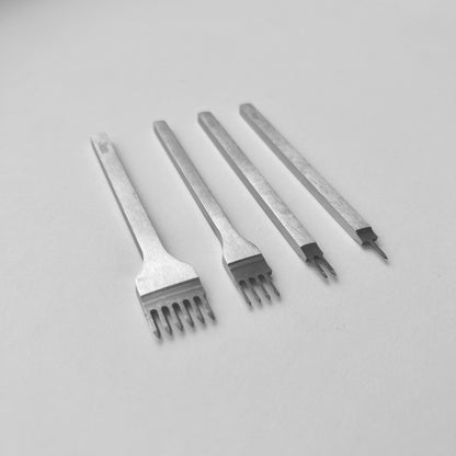 Set of four metal leather stitching punches on a light grey background