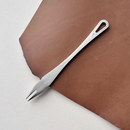 Metal distance gauge tool on a piece of leather