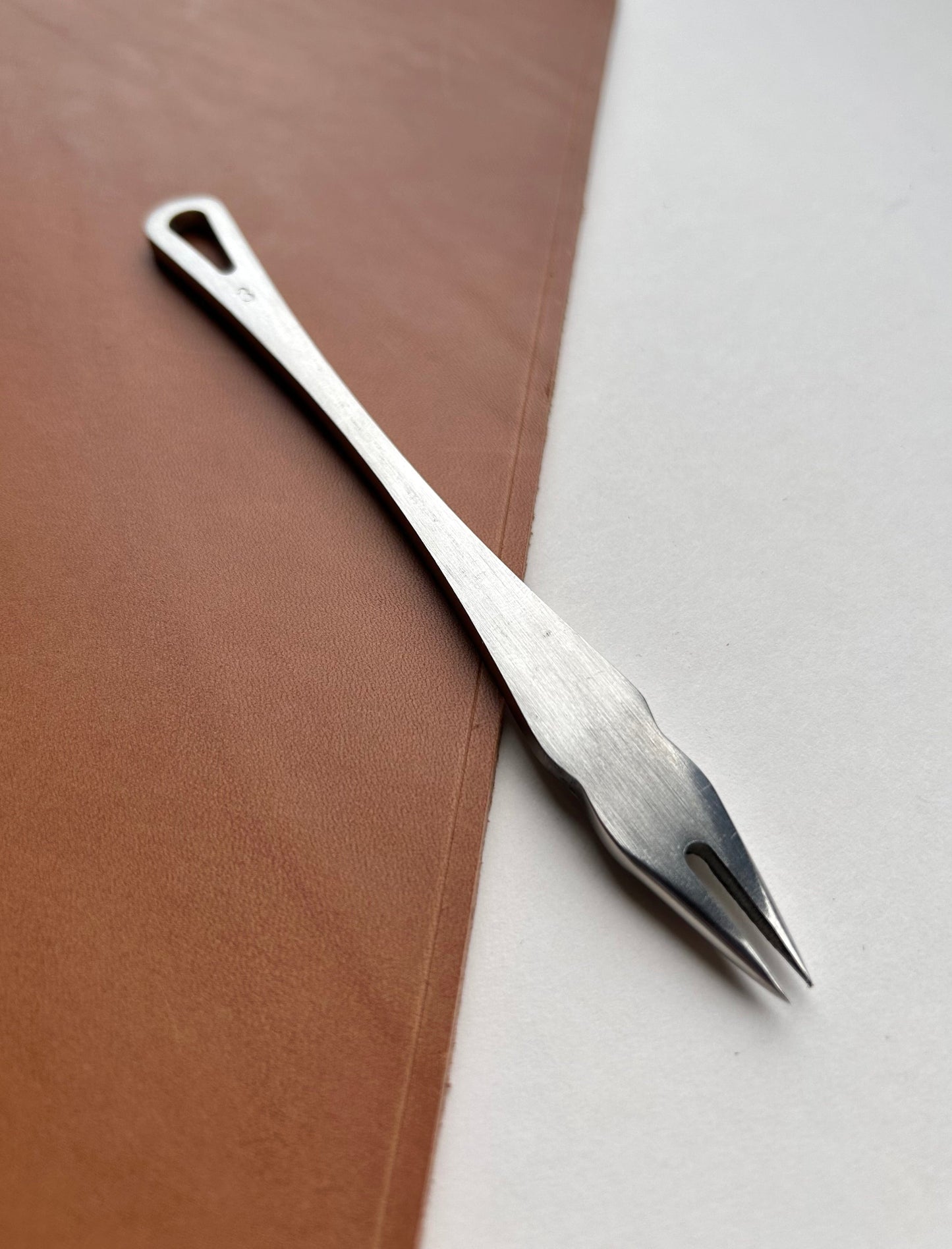 Metal distance gauge tool on a piece of leather