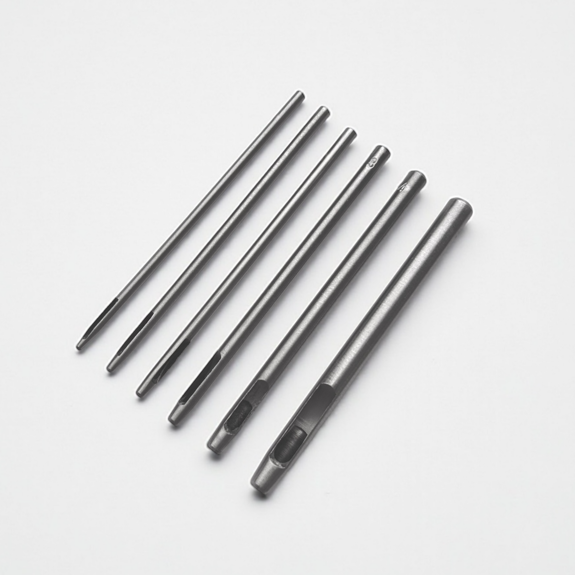 Set of six silver leather drive punches on a white background