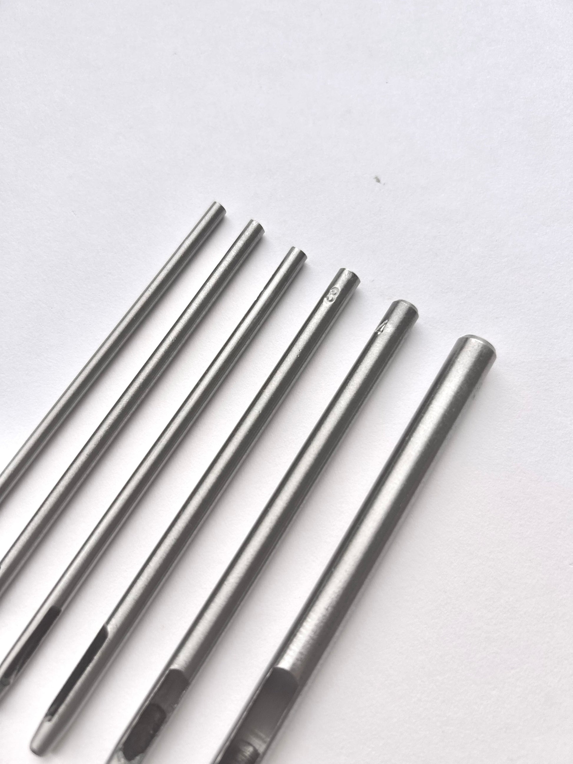 Set of six silver leather drive punches on a white background