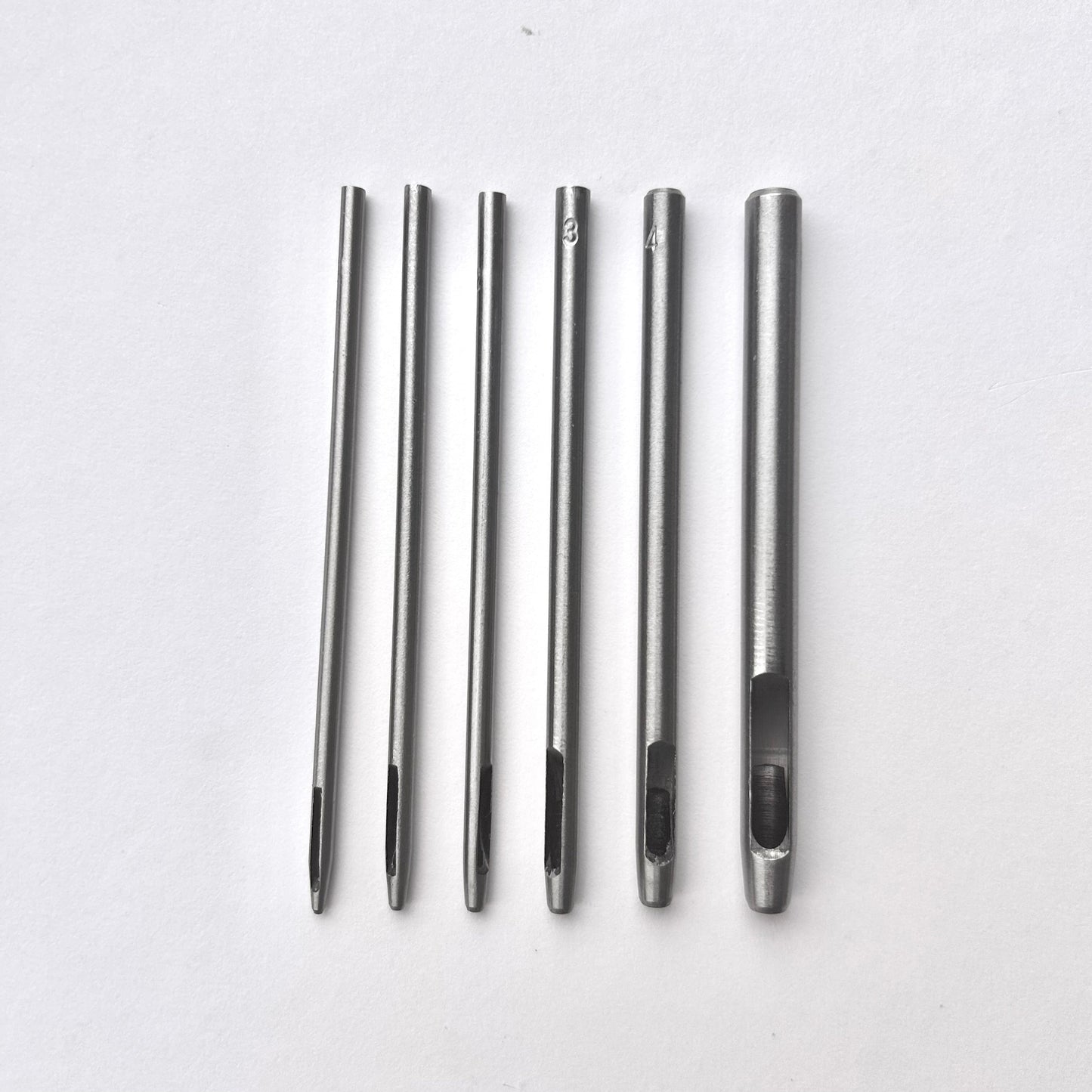 Set of six silver leather drive punches on a white background