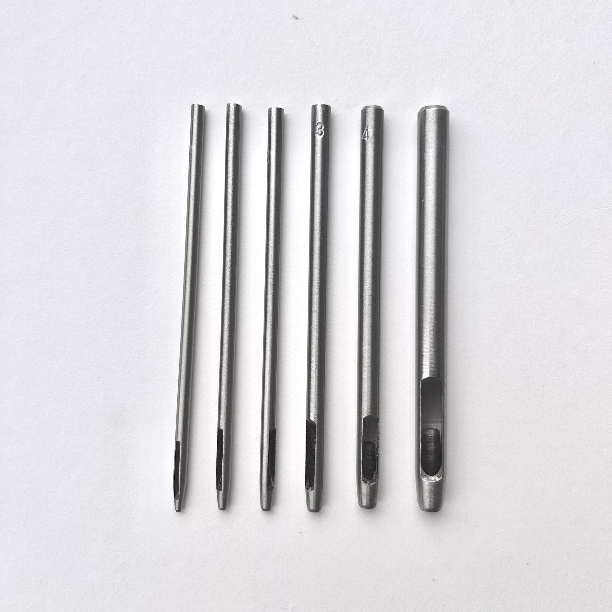 Set of six silver leather drive punches on a white background