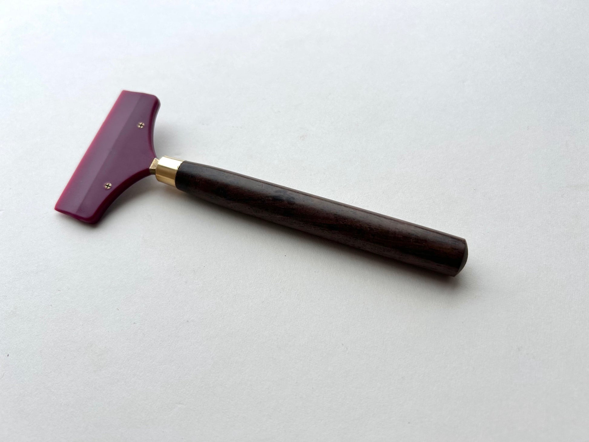 Leather glue spreader tool with purple blade and black wooden handle on a white background