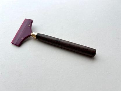 Leather glue spreader tool with purple blade and black wooden handle on a white background