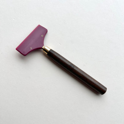 Leather glue spreader tool with purple blade and black wooden handle on a white background