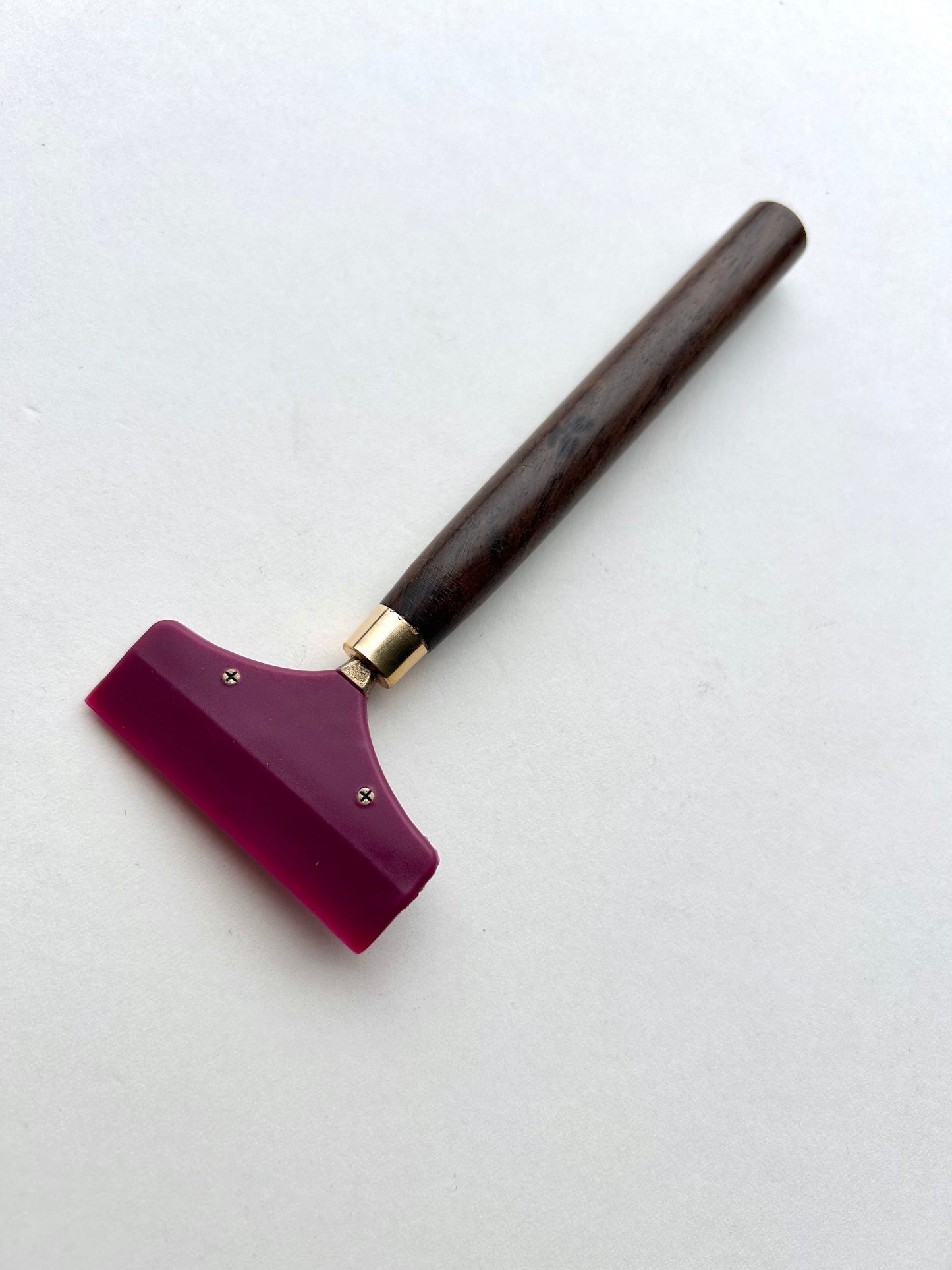 Leather glue spreader tool with purple blade and black wooden handle on a white background