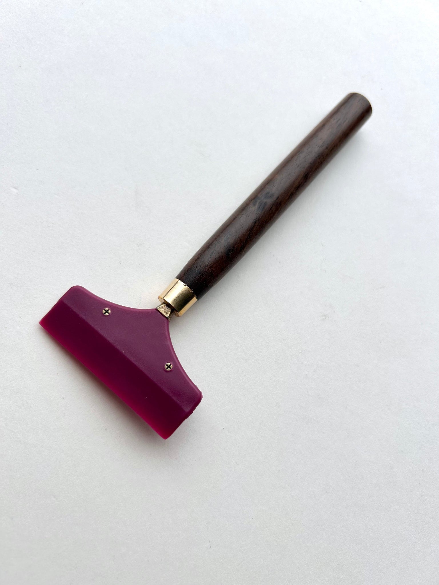 Leather glue spreader tool with purple blade and black wooden handle on a white background