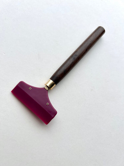 Leather glue spreader tool with purple blade and black wooden handle on a white background