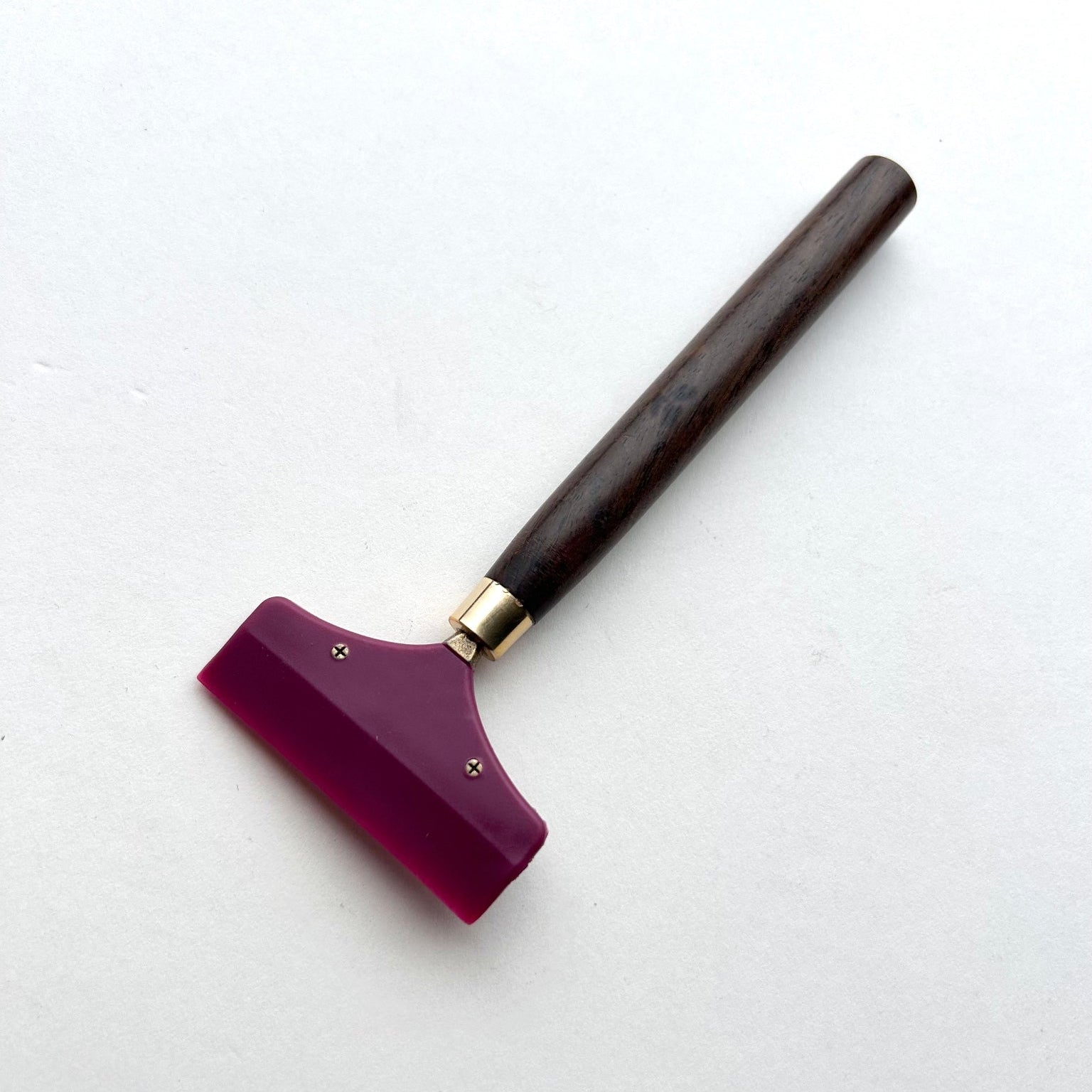 Leather glue spreader tool with purple blade and black wooden handle on a white background