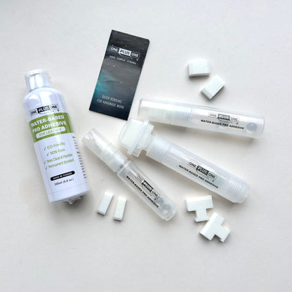 Collection of One Plus One brand water-based adhesive products on a light gray background