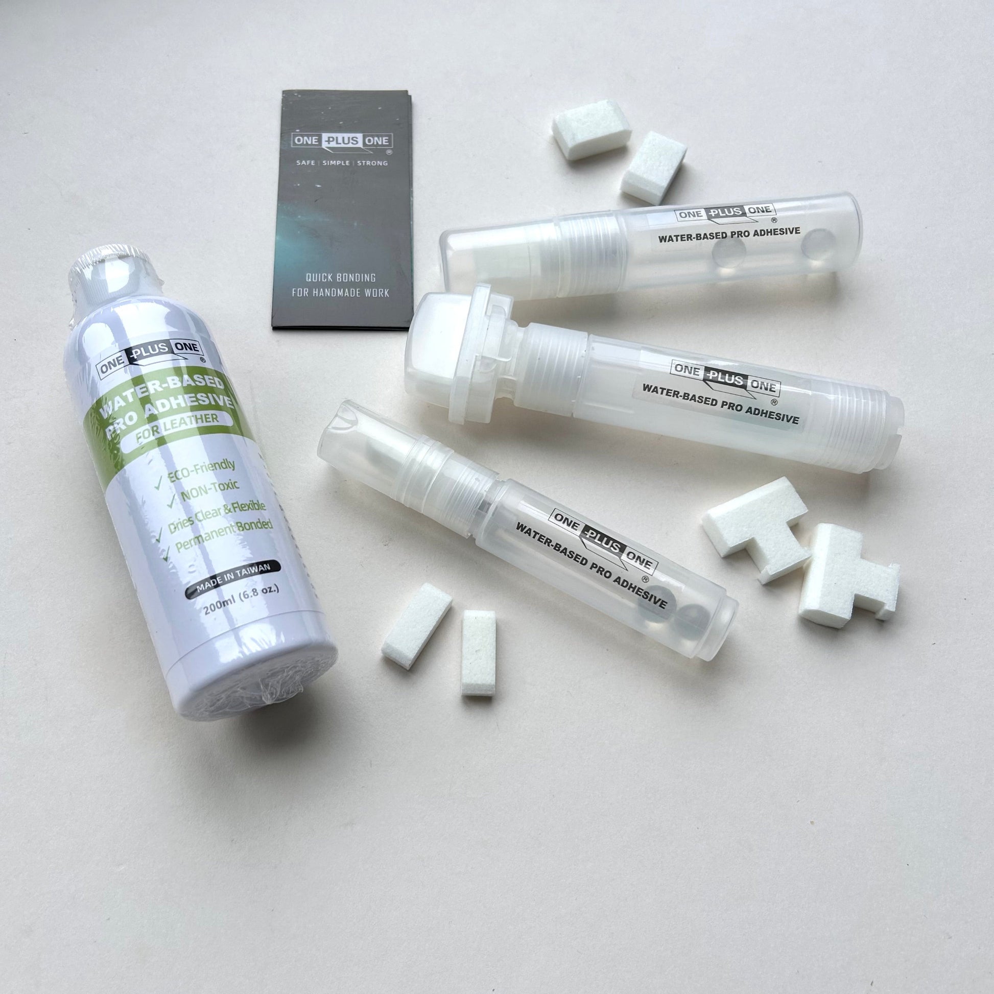 Set of adhesive products including bottles and tubes on a light gray background