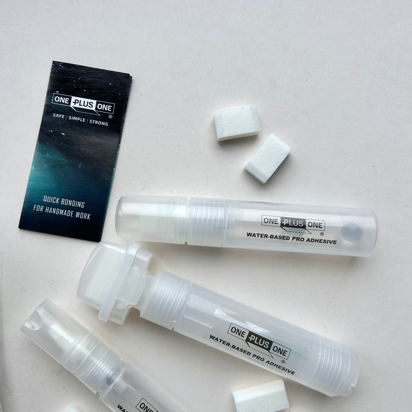 Three tubes of 'One Plus One' adhesive on a light gray background