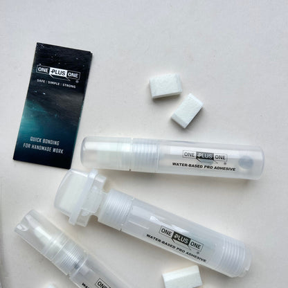 Three tubes of 'One Plus One' adhesive on a light gray background