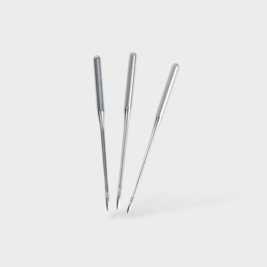 Three metal sewing machine needles on a white background