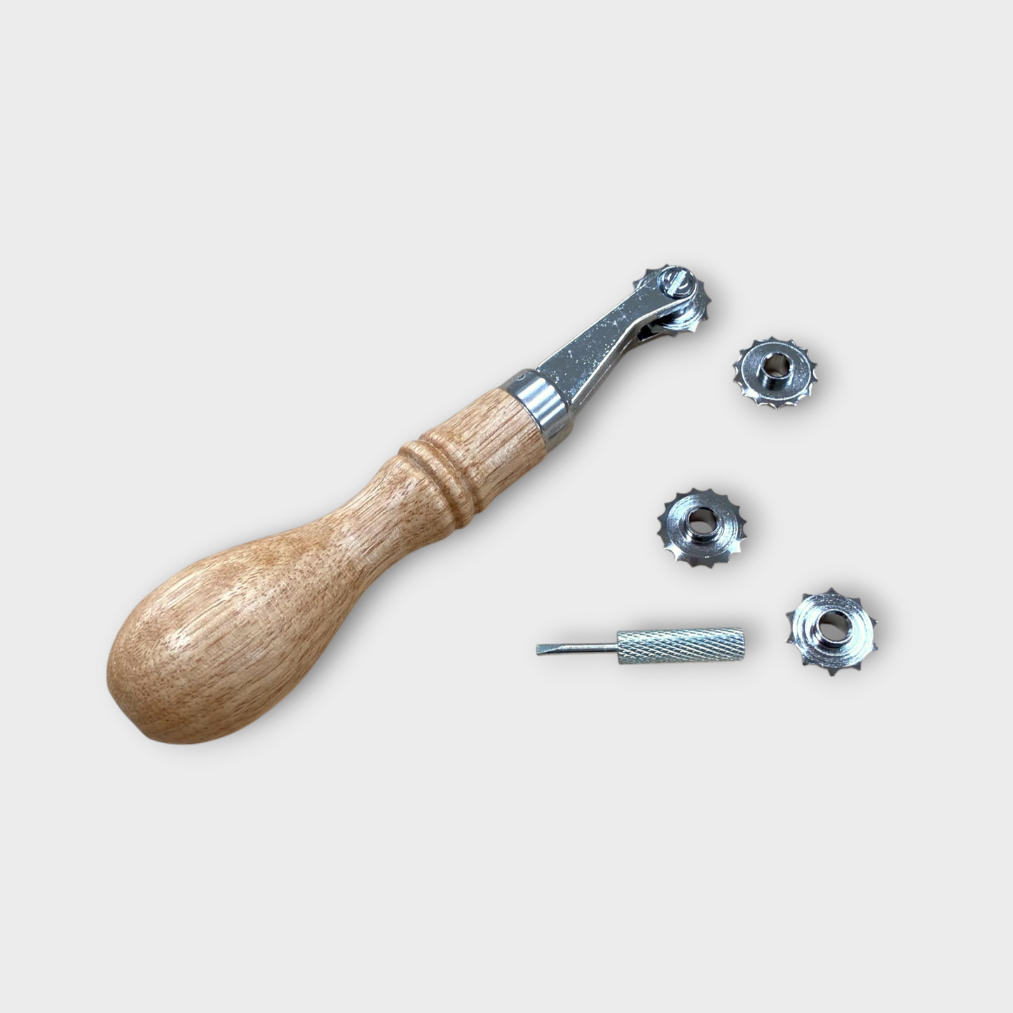 Wooden handle leather stitch spacer tool with metal components on a light beige background