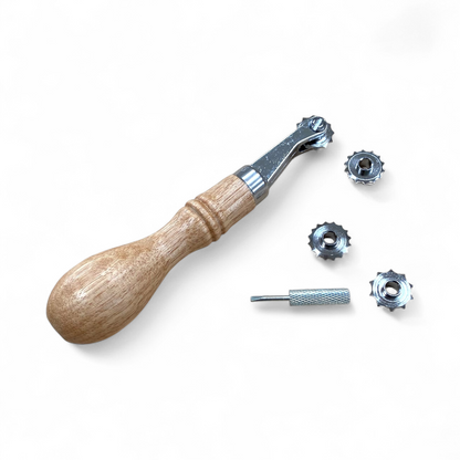 Wooden handle leather stitch spacer tool with metal components on a light beige background