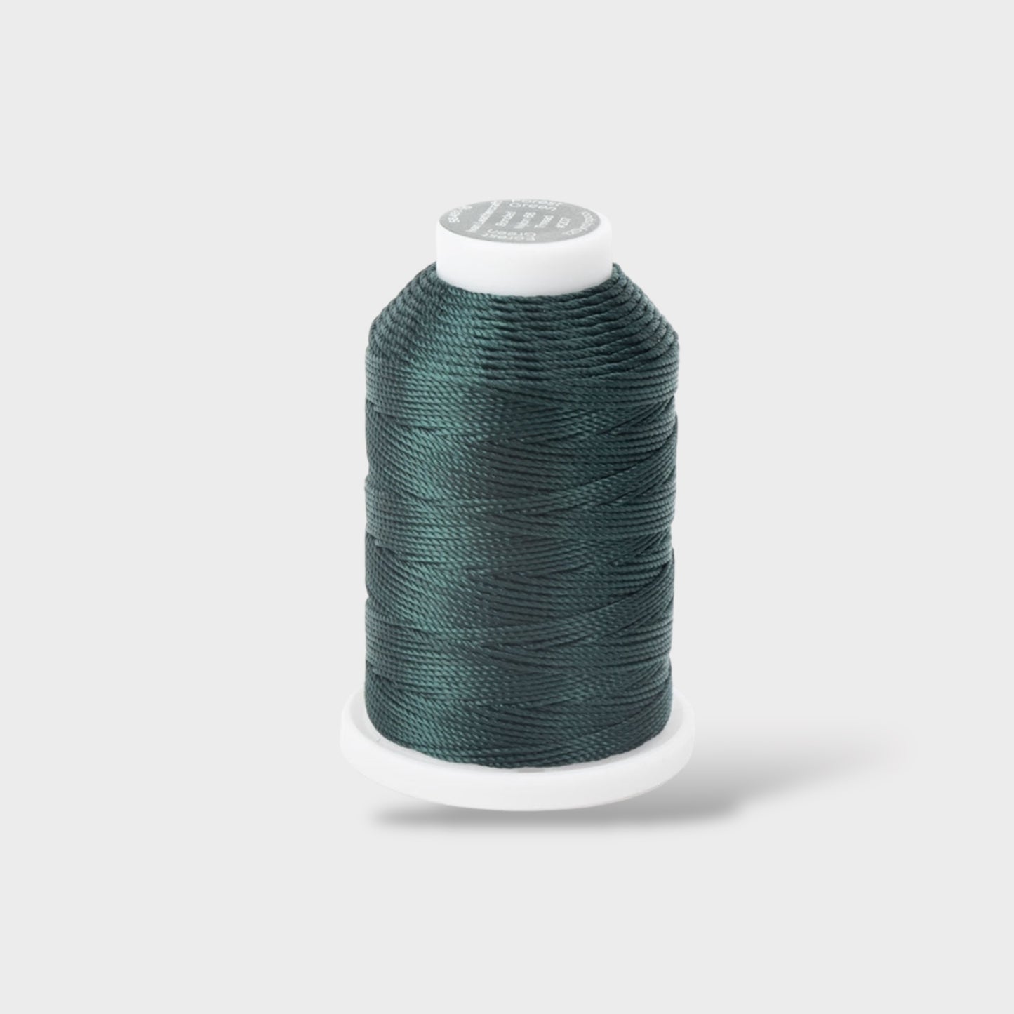 Spool of teal thread on a white background