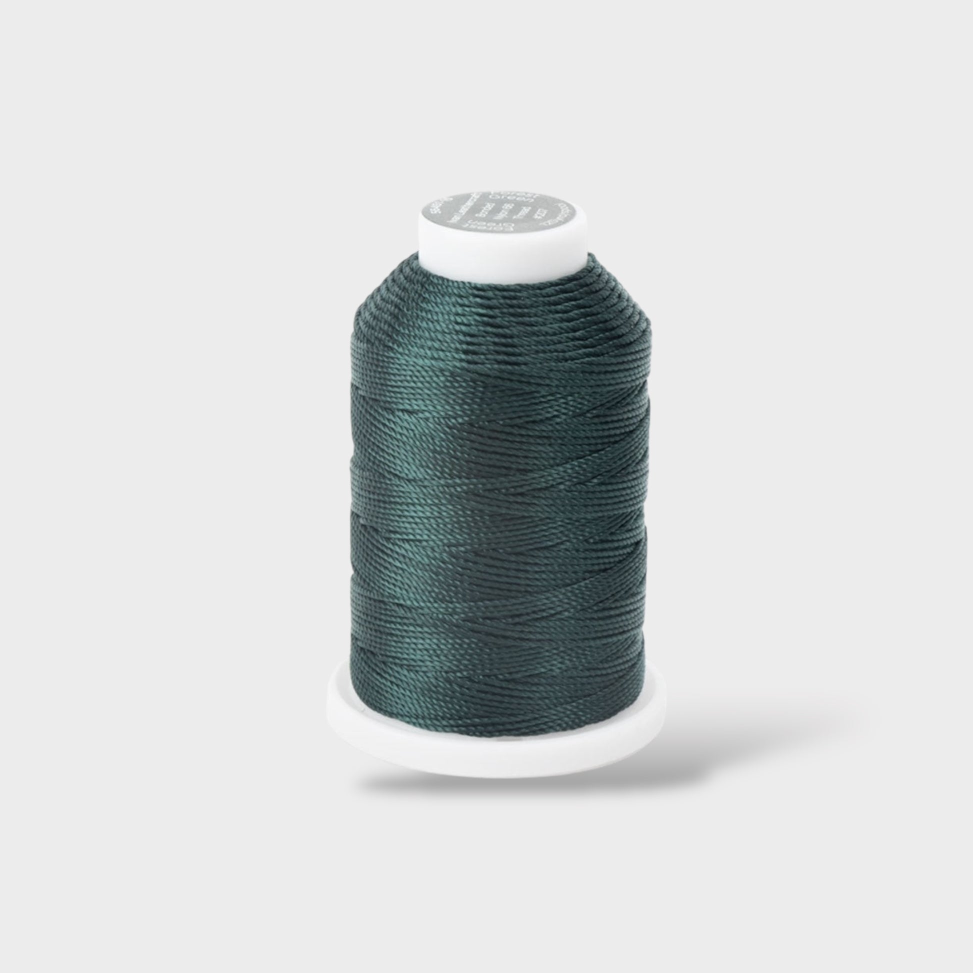 Spool of teal thread on a white background