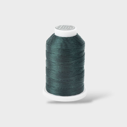 Spool of teal thread on a white background