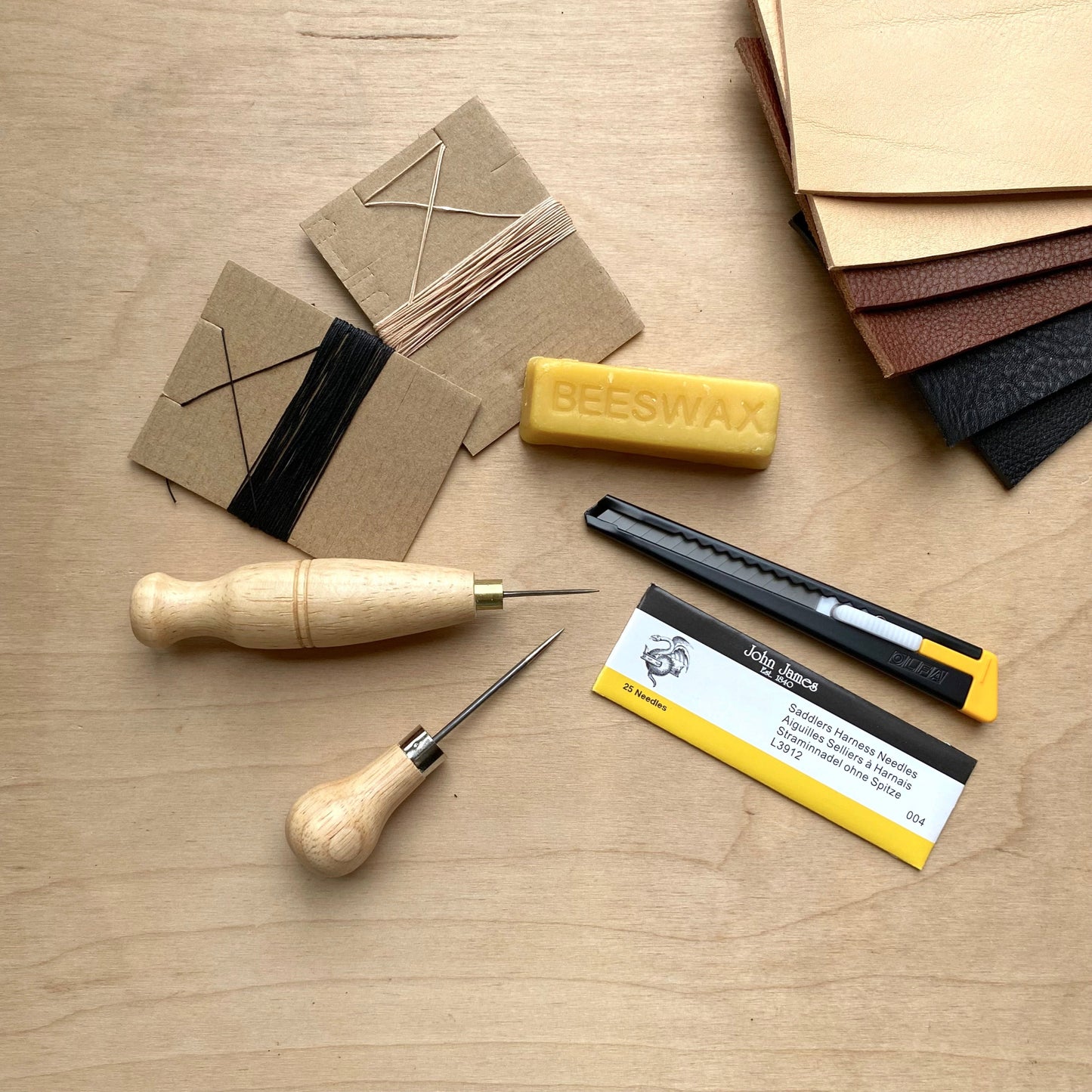 Set of tools and materials for leatherworking on a wooden surface