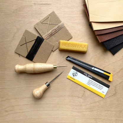 Set of tools and materials for leatherworking on a wooden surface