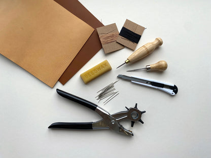 Set of leatherworking tools and materials on a white surface