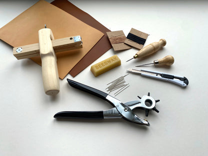 Collection of leatherworking tools on a white surface