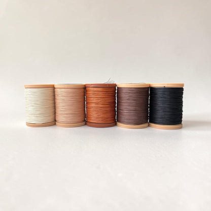 Five spools of Meisi Original Linen thread for saddle stitching leather in different colours on a white background