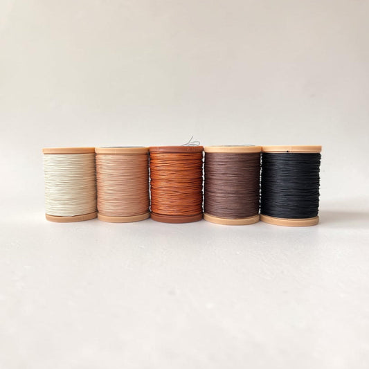 Five spools of Meisi Original Linen thread for saddle stitching leather in different colours on a white background