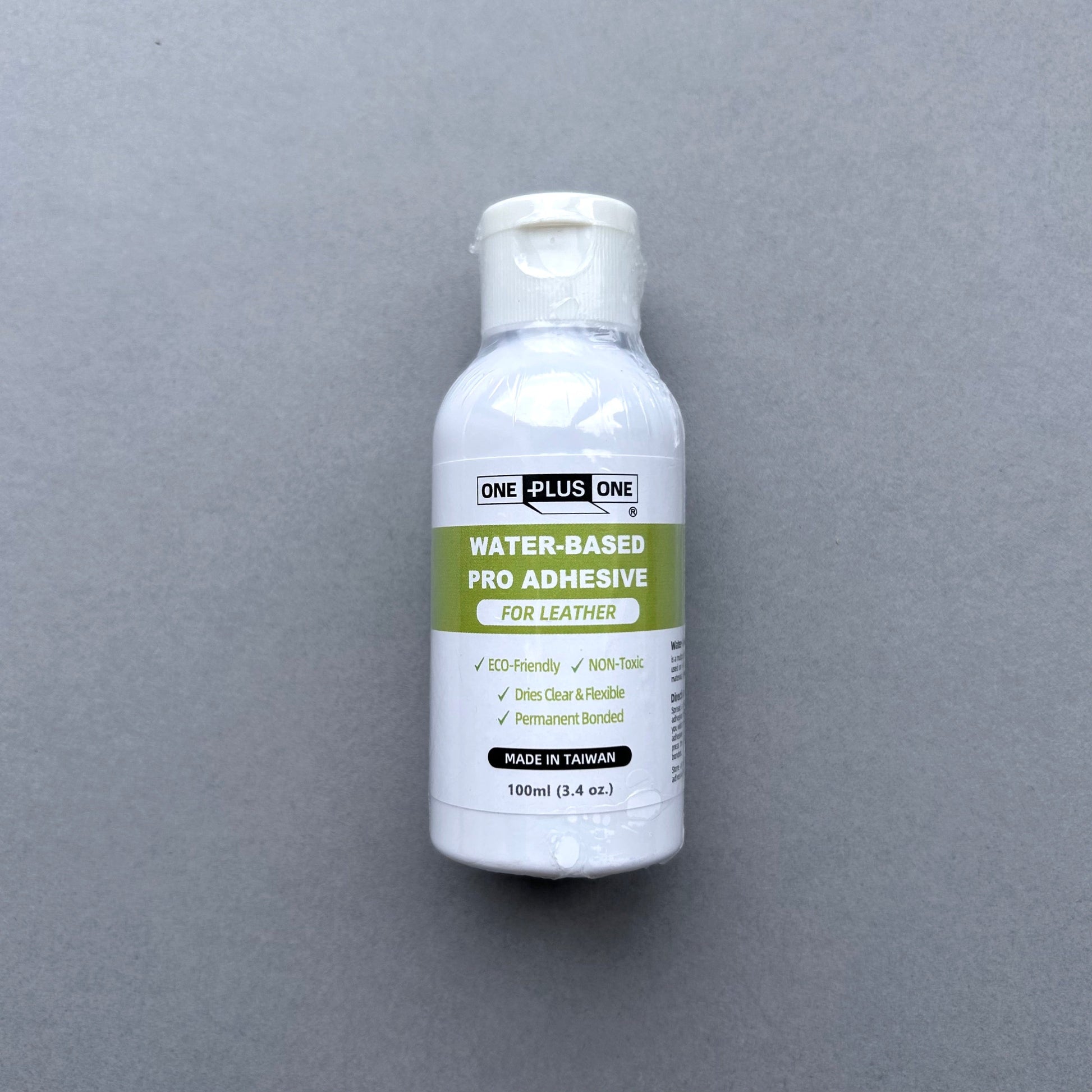 Bottle of water-based pro adhesive for leather on a gray background